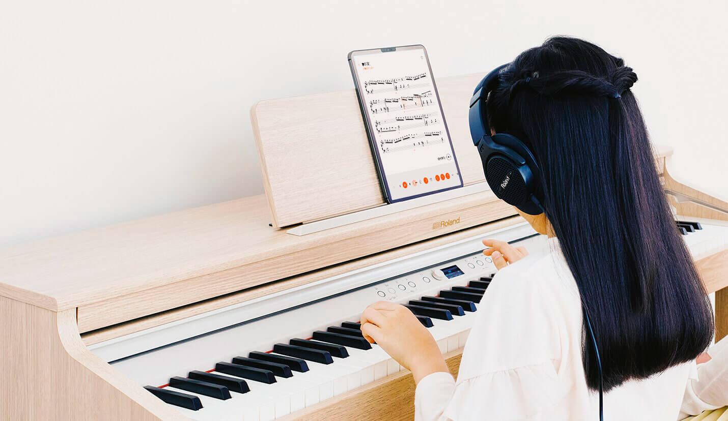 電子ピアノの上に置かれたタブレットを見ながらピアノ演奏
